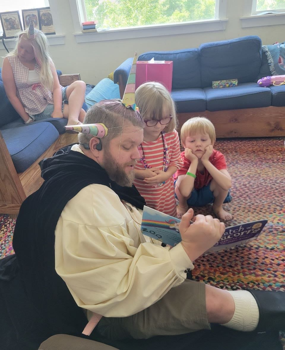 Costumed storyteller in a unicorn horn reading to captivated kids